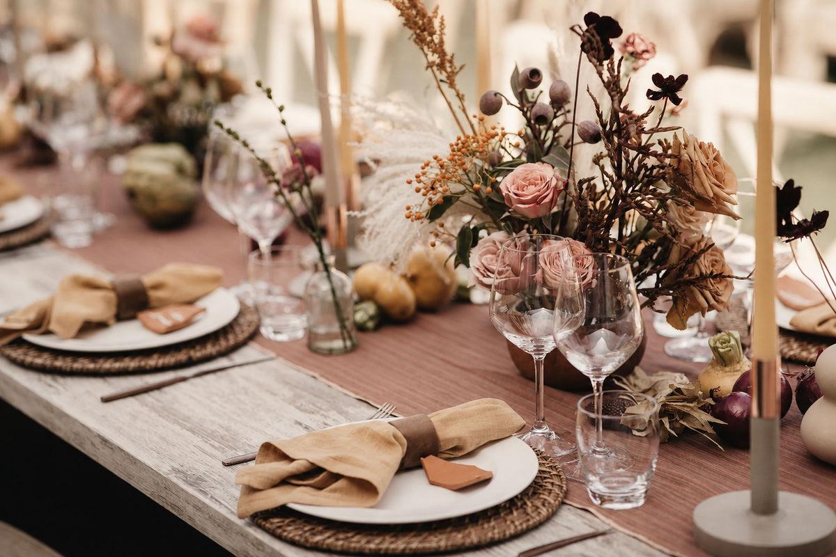 Long dining table set with linen napkins, glassware and dried flower centrepieces for a sit-down dinner. Cuseho sit down catering, Singapore