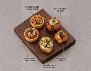 The Garden canapes on a wooden board, labelled Roasted Carrot & Harissa Tartlet and 4 more. Cuseho canape catering, Singapore