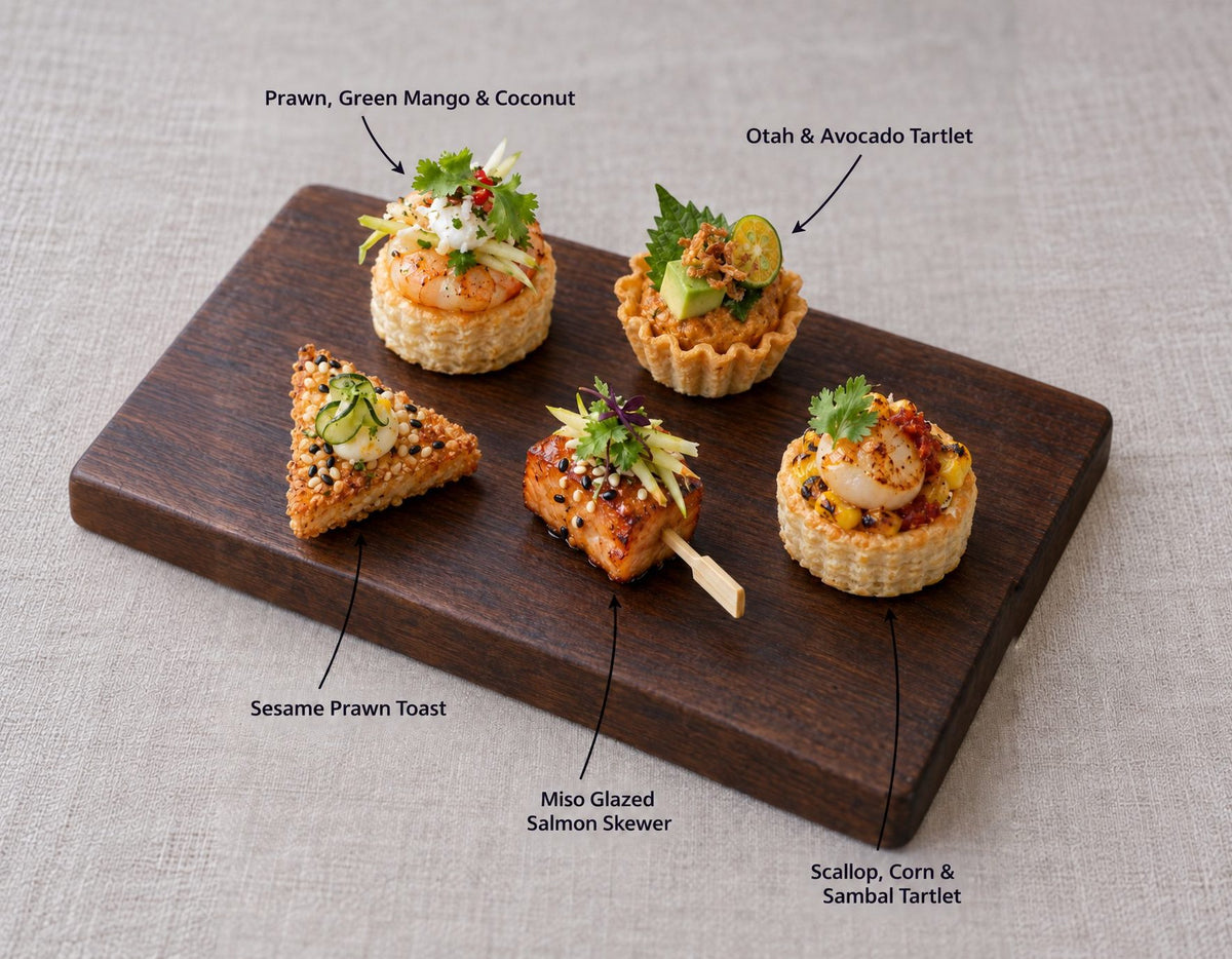 The Sea canapes on a wooden board, labelled Prawn, Green Mango & Coconut and 4 more. Cuseho canape catering, Singapore